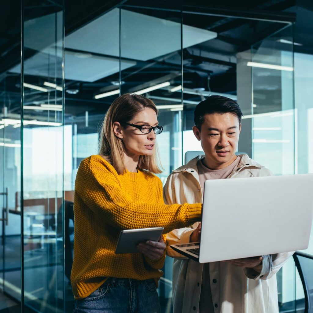 Two colleagues reviewing a project on a laptop and tablet